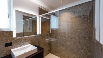 Un bagno moderno con doccia vetrata, lavandino bianco e un ampio specchio.