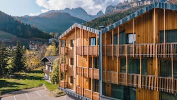 Un edificio moderno de madera con balcones, con montañas al fondo.