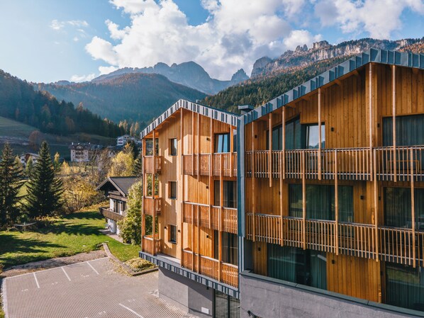 Un edificio moderno de madera con balcones, con montañas al fondo.