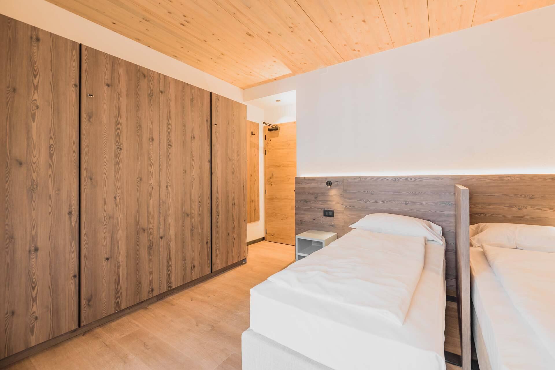 Une chambre avec des murs en bois, un lit et une table de chevet.