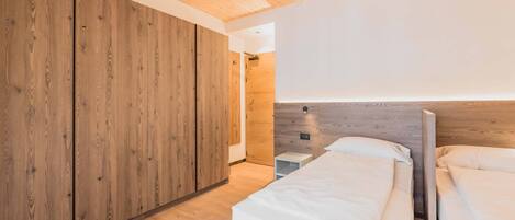 A bedroom with wooden walls, a bed, and a bedside table.