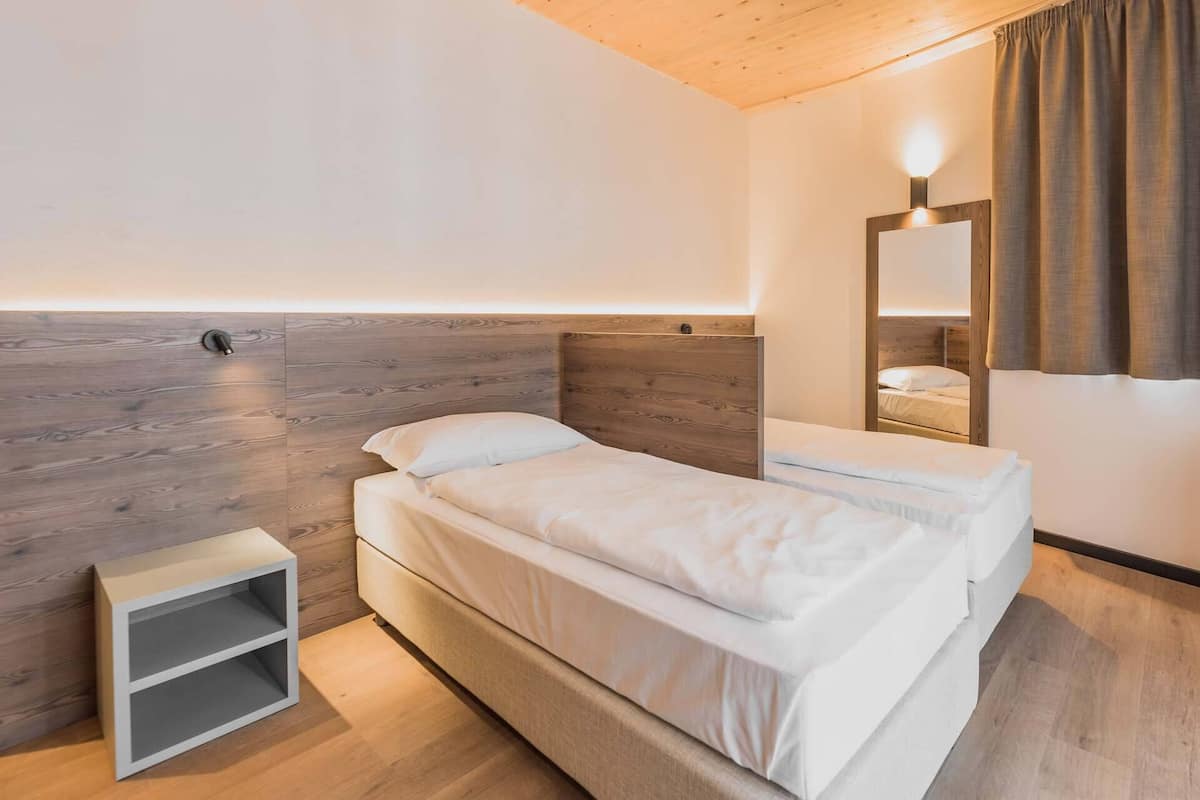 Un dormitorio moderno con cabecera de madera, una mesita de noche y un espejo.