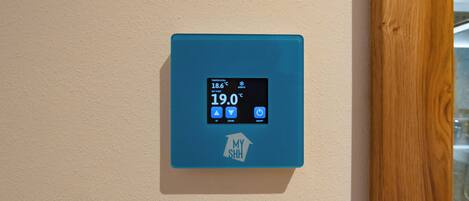 A thermostat mounted on a wall displaying a temperature of 19.0°C.