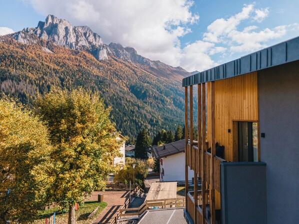 Un edificio moderno con fachada de madera y un balcón con vistas a un paisaje montañoso.