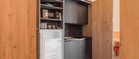 Una cocina compacta equipada con refrigerador, microondas y estufa.