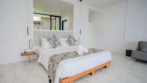 A modern bedroom with a large bed, a bedside table, a mirror, and a grey sofa. - Gandum Uluwatu Luxury Boutique Stay - Gandum Villa Complex (Pecatu)