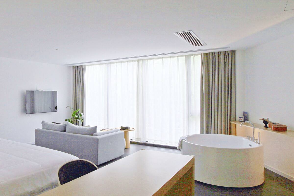 Une chambre d’hôtel équipée d’un lit, d’un canapé, d’un bureau, d’une baignoire et d’un téléviseur.
