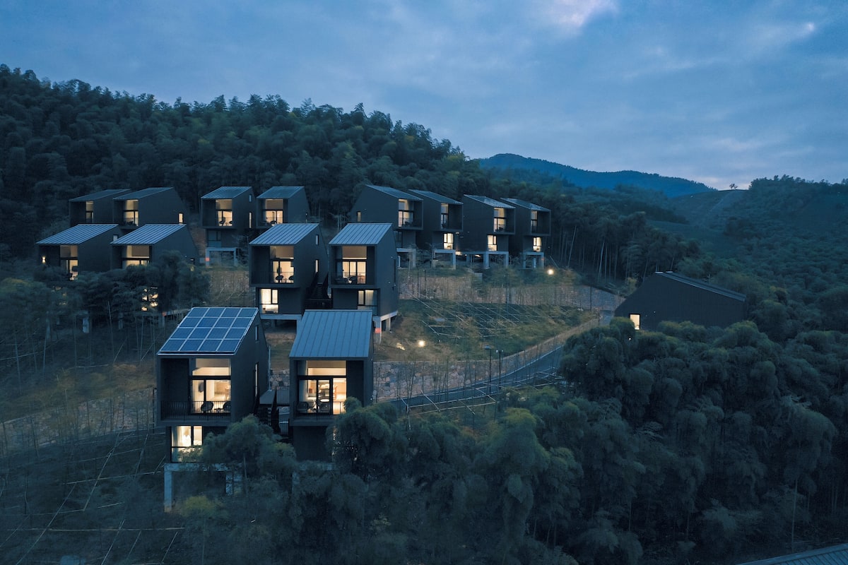 Un complexe résidentiel moderne composé de plusieurs maisons à deux étages, chacune dotée de grandes fenêtres et de panneaux solaires.