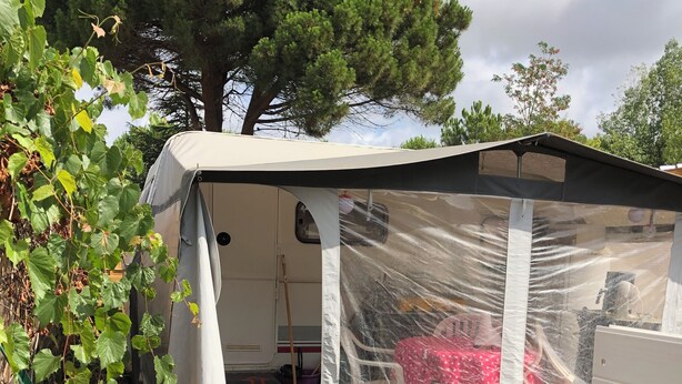 A covered outdoor area with a tent, a sink, and a paved walkway.