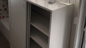 A compact kitchenette with a small countertop, a window with a sheer curtain, and a microwave.