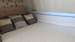 A bunk bed with a white mattress and patterned pillows.