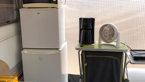 A compact kitchenette with a microwave, refrigerator, coffee maker, and fan.
