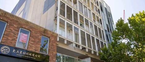 A multi-story building with a modern architectural design, featuring a mix of glass and brick facades.