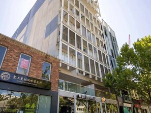 A multi-story building with a modern architectural design, featuring a mix of glass and brick facades. - Central 2BR Near Queen Victoria Market (Melbourne)