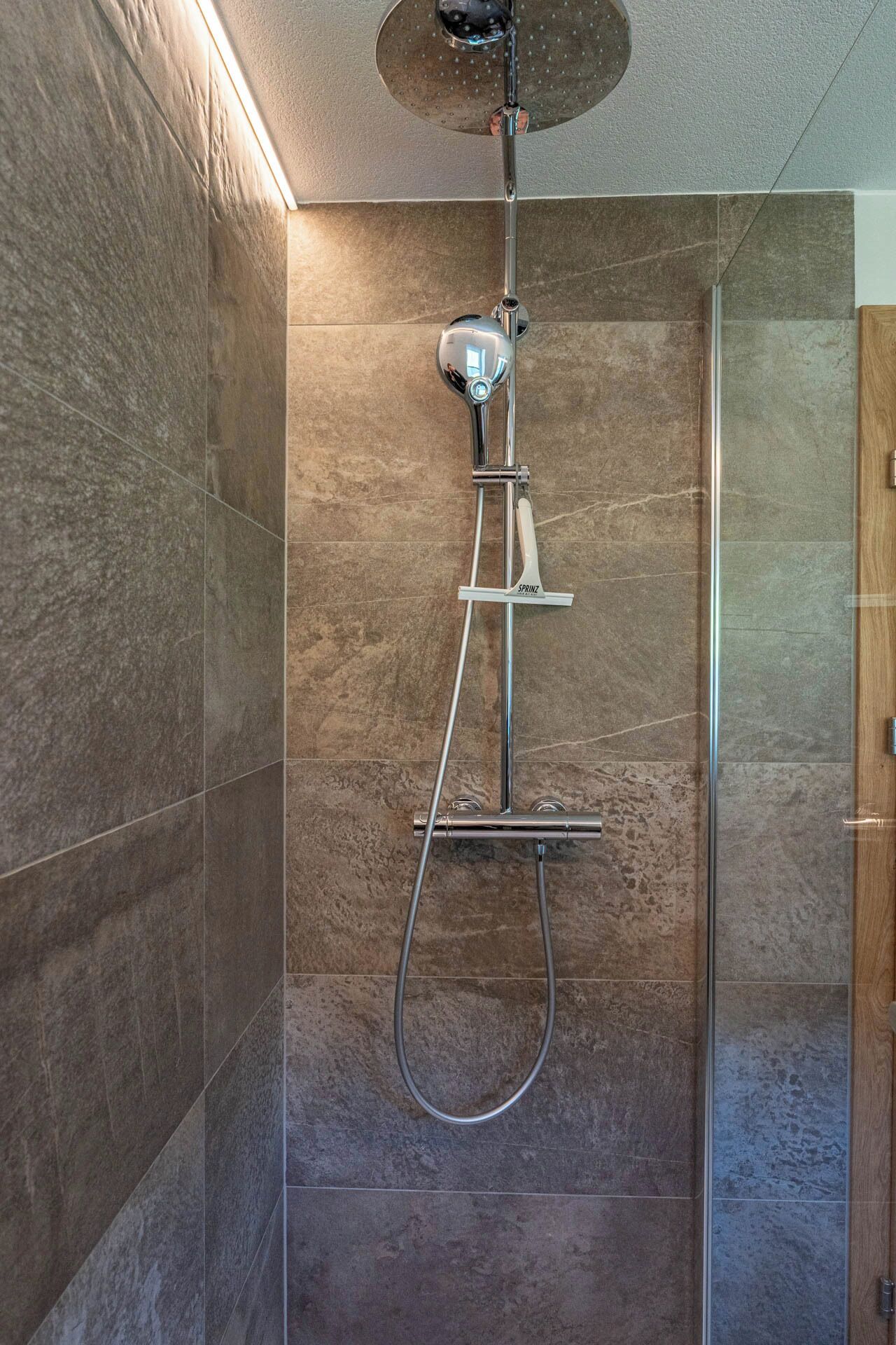 A modern shower enclosure with a handheld showerhead and a rain shower attachment.