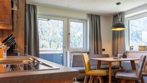 A modern kitchen with a wooden countertop and a dining area with a table and chairs. - Maurig Appartement (Elbigenalp)