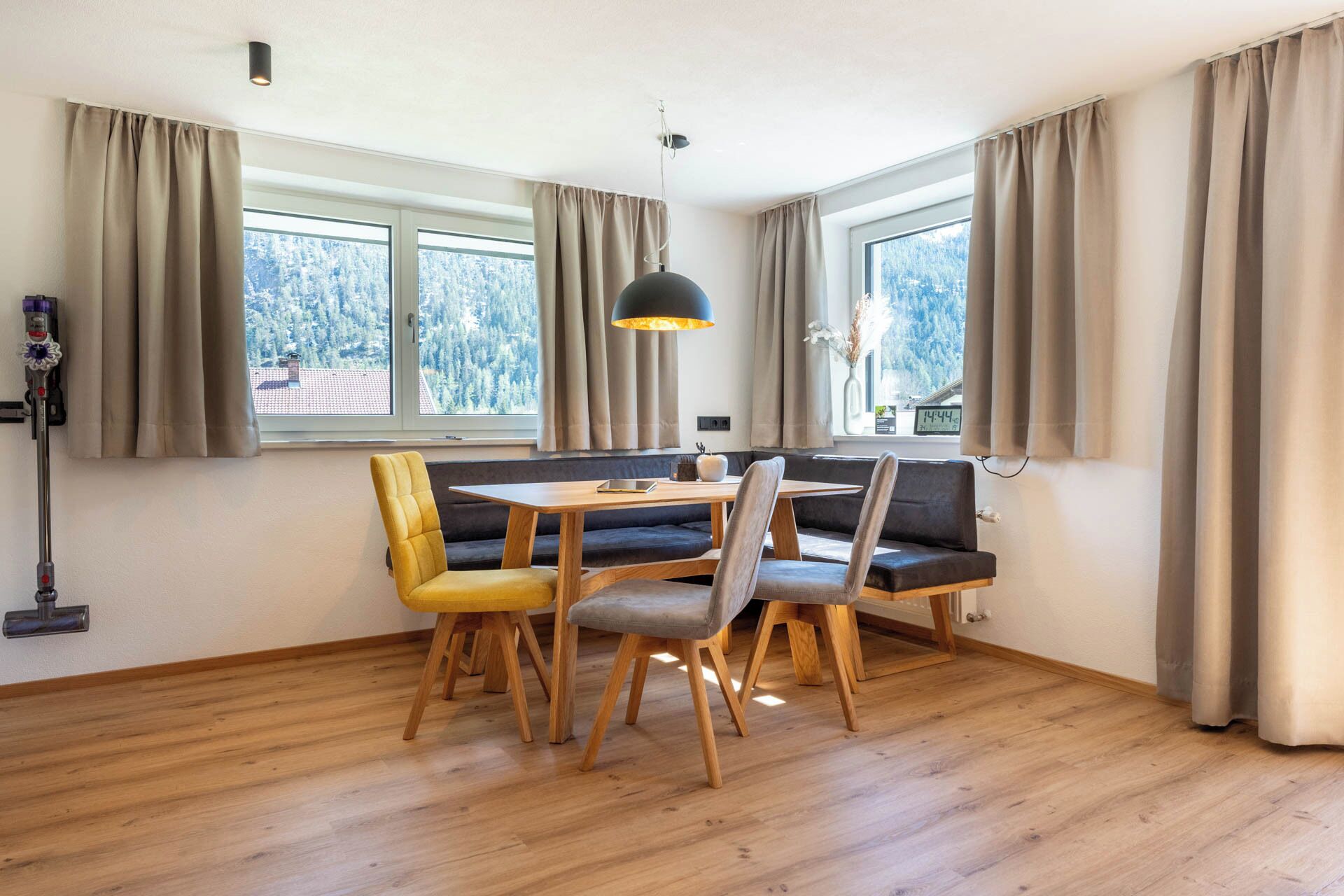Ein Essbereich mit Holztisch und -stühlen, einer Bank und einer Pendelleuchte.