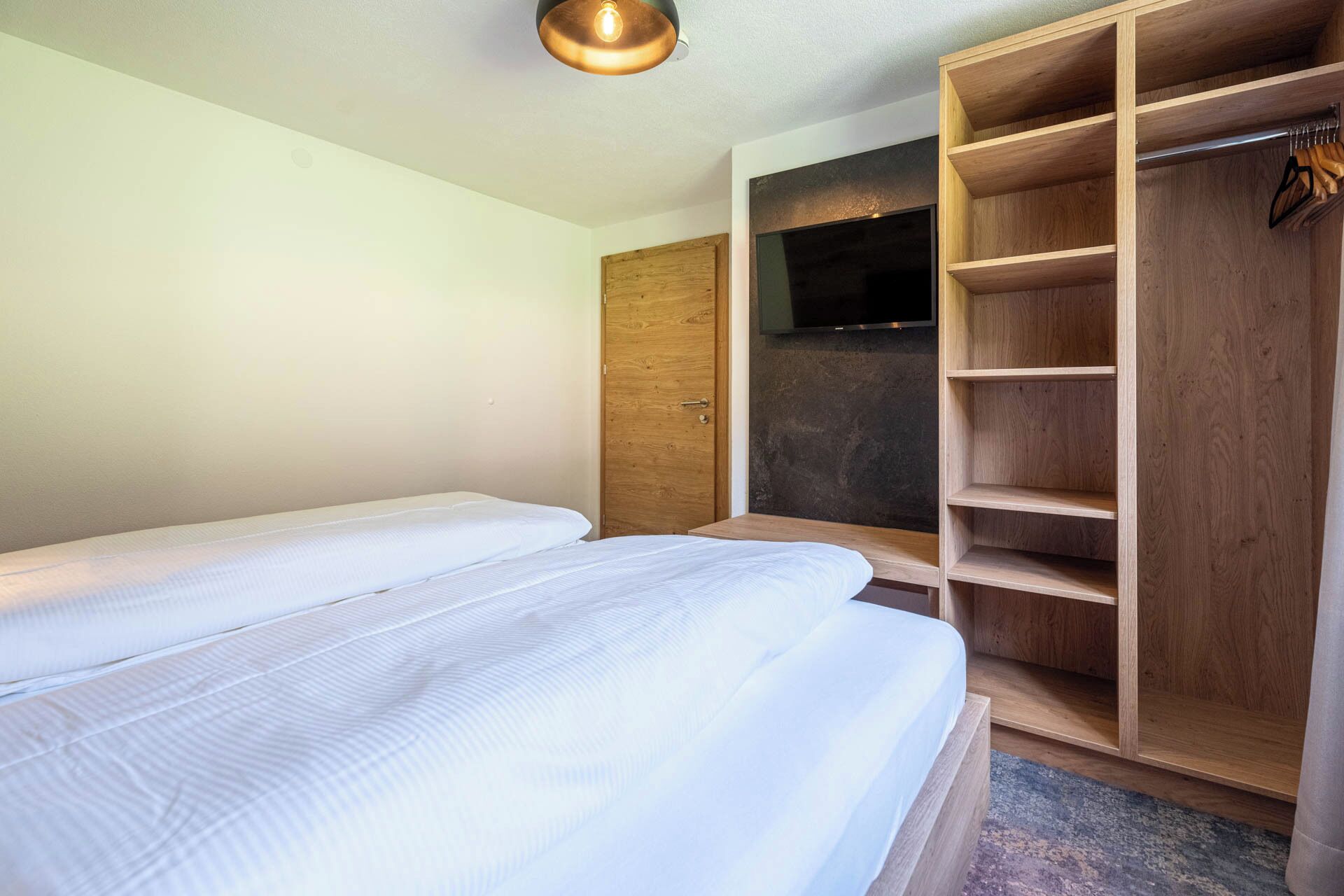 Camera da letto con due letti, un armadio in legno e una televisione.
