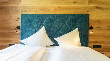 A bed with a quilted teal headboard, two white pillows, and a white bedspread.