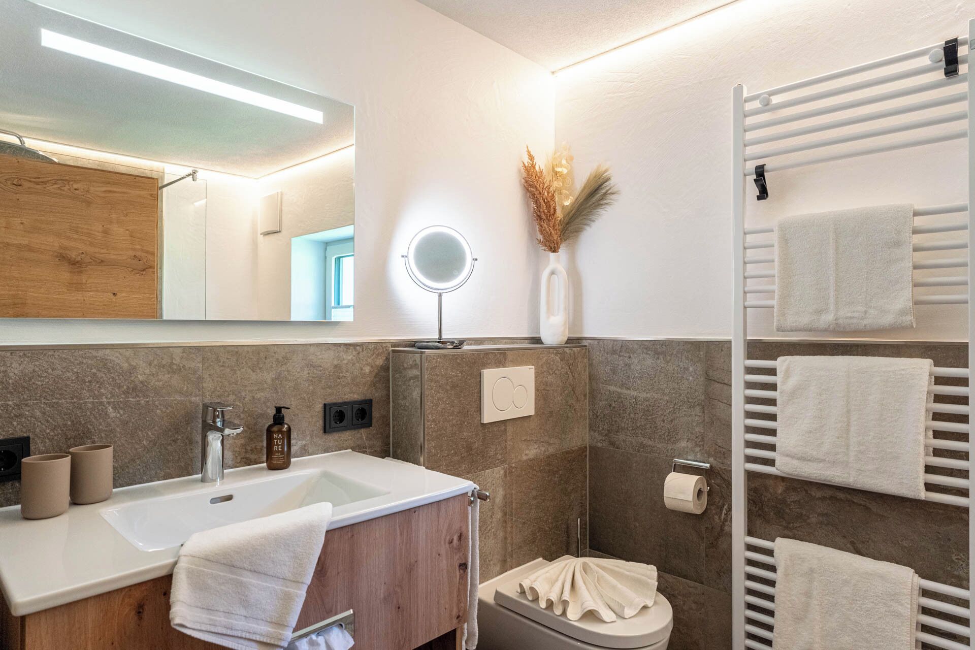 A modern bathroom with a vanity, sink, mirror, and towel rack.