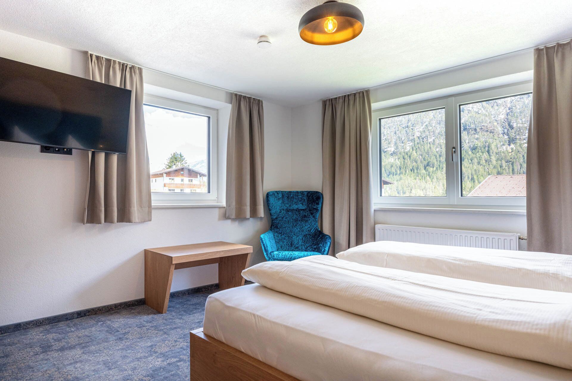 Una habitación de hotel con una cama, una silla, un escritorio y un televisor montado en la pared.