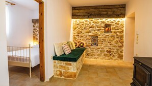 Una habitación acogedora con pared de piedra, un banco de madera y una cama.