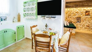 Un comedor con una mesa preparada para dos personas, un televisor montado en la pared y una pared de piedra con adornos.