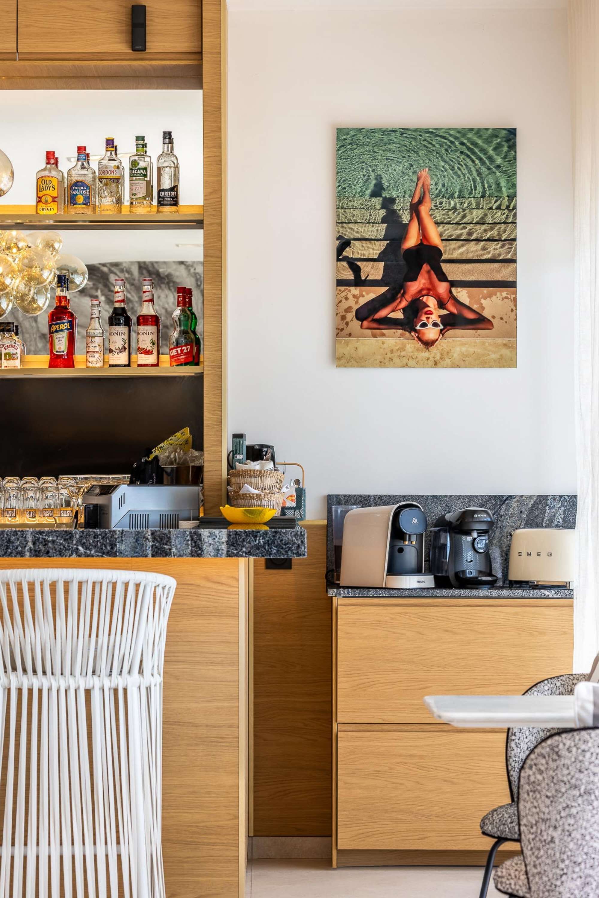 Una cocina moderna con encimera de mármol, una cafetera y un cuadro de una mujer en una postura de yoga en la pared.