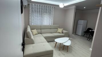 Een moderne woonkamer met een hoekbank, een salontafel en een eethoek.