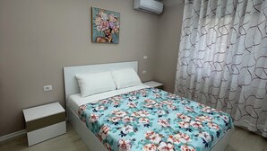 A bedroom with a bed, a nightstand, a wall-mounted air conditioner, and a ceiling light fixture.