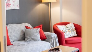 Una sala moderna con un sofá gris, un sillón rojo y una mesa de centro de madera.
