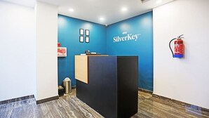 A reception area with a blue wall, a reception desk, and a fire extinguisher mounted on the wall. - Moody moon blue (Gurugram)