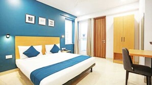 A hotel room with a bed, a desk, and a wardrobe. - Moody moon blue (Gurugram)