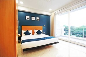 Una camera da letto con un letto, un comodino, una mensola a parete e un'ampia finestra con vista.
