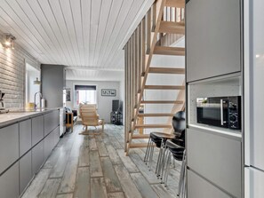 A modern kitchen with a built-in microwave, wooden staircase, and a seating area with chairs. - 5 Star Holiday Home in Lokken (Lokken)