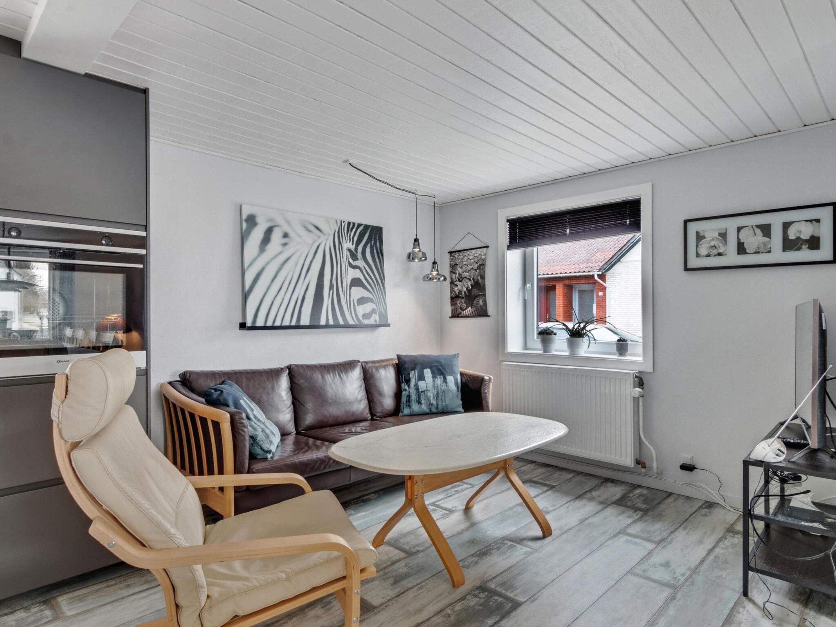 A modern living room with a sofa, chairs, a round table, and artwork on the walls.