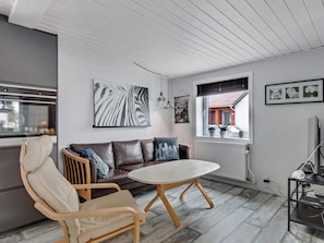 A modern living room with a sofa, chairs, a round table, and artwork on the walls. - 5 Star Holiday Home in Lokken (Lokken)