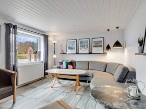 A modern living room with a sectional sofa, a round coffee table, and a view of the outdoors. - 5 Star Holiday Home in Lokken (Lokken)