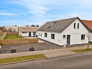 A single-story white building with a sloped roof, a small porch, and a number '21' sign. - 5 Star Holiday Home in Lokken (Lokken)
