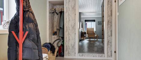 A hallway with a wooden bench, a coat rack, and a door leading to another room.