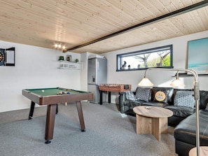 A room with a pool table, a foosball table, a sofa, a coffee table, and a window with a view. - 5 Star Holiday Home in Lokken (Lokken)
