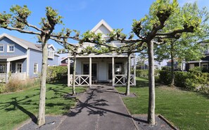 A residential property with a covered porch, a pathway leading to the entrance, and a lawn. - Bungalow in South Holland by the Water (Simonshaven)
