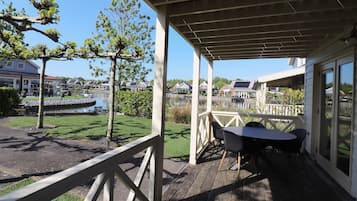 A covered outdoor area with a table and chairs, overlooking a body of water and residential buildings.
