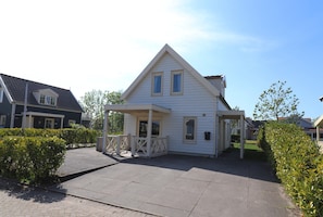 Eenlaags huis met een puntdak, een overdekte veranda en een kleine voortuin.