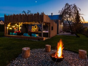 A wooden outdoor seating area with a '20th Century Fox' sign, a fire pit, and a grassy lawn. - Apartment in Moravia Near Ostrava Town (Frydlant nad Ostravici)