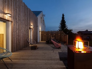A wooden deck with outdoor seating, a fire feature, and a modern building with vertical wooden siding. - Apartment in Moravia Near Ostrava Town (Frydlant nad Ostravici)