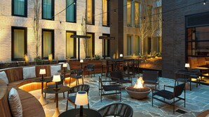 Ein Außenbereich mit Terrasse, Sitzgelegenheiten, Tischen und einem Feuerkorb.