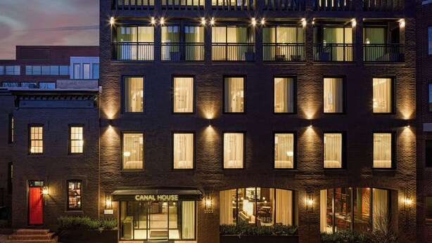 Ein Hotel mit Ziegel Fassade, zahlreichen Fenstern und einer roten Tür.