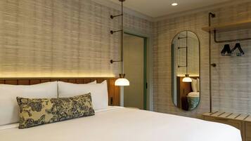A hotel room with a large bed, a mirror, a hanging light fixture, and a wardrobe.