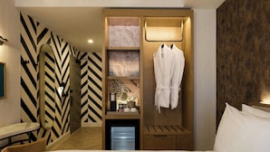 Ein Hotelzimmer mit Bett, kleinem Tisch, integriertem Kleiderschrank und Spiegel.